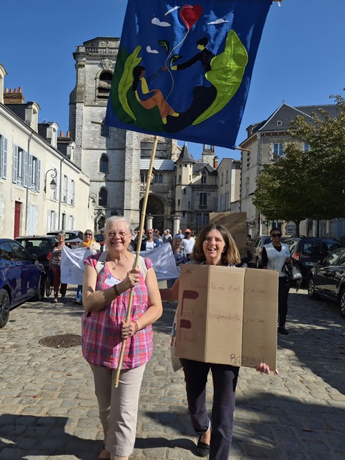 Deux bénévoles de l'équipe d'Orléans Sud brandissent fièrement en tête de cortège la bannière que leur équipe a elle-même réalisée.
