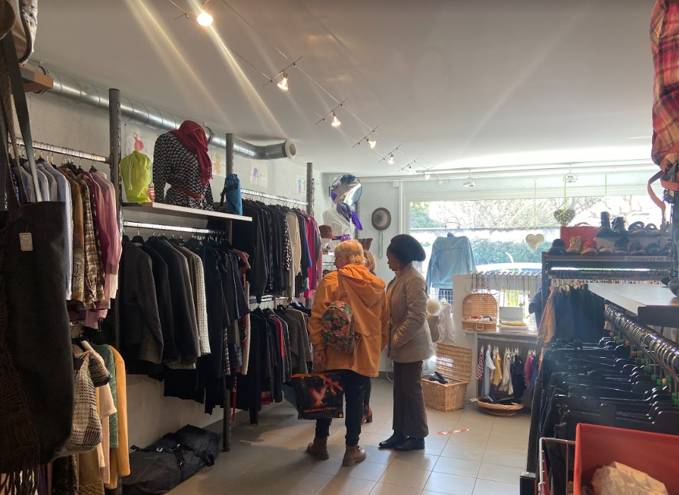 photo de l'intérieur d'une boutique de vêtements solidaires avec deux bénévoles