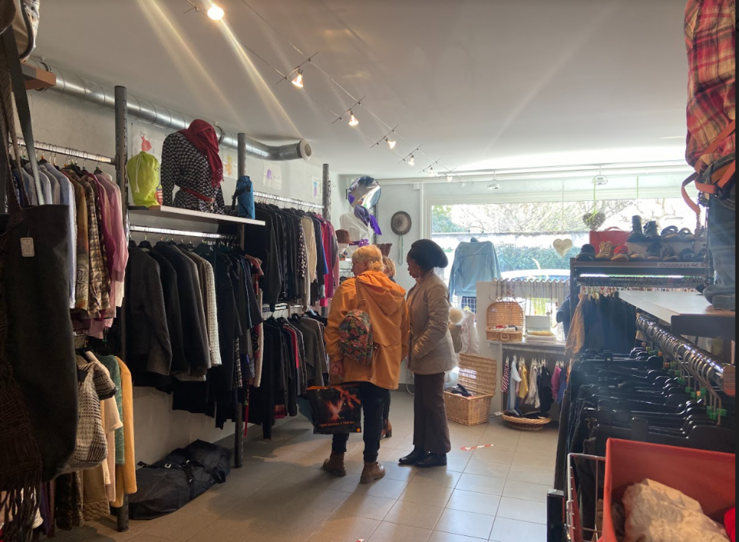 photo de l'intérieur d'une boutique de vêtements solidaires avec deux bénévoles