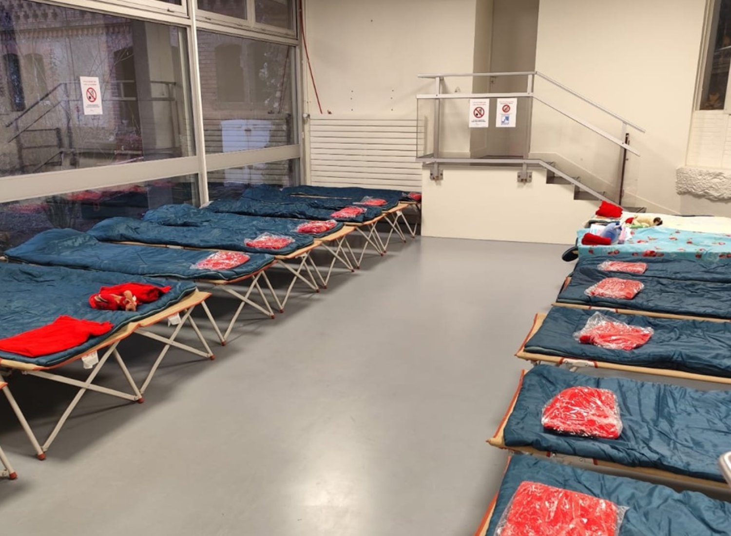 Dortoir de l'accueil de nuit avec sacs de couchage sur chaque lit pliable